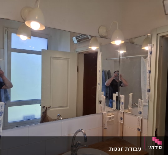 מראה חדשה מותקנת בחדר אמבטיה עם תאורה